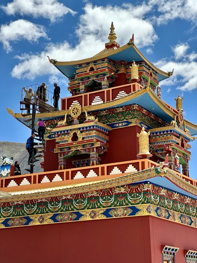Riders climbing the stairs of a colourful Buddhist monastery